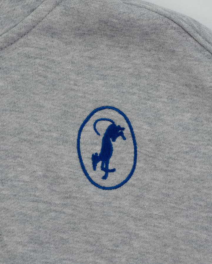 Close-up of a heather gray sweatshirt featuring a navy blue embroidered logo of a greyhound inside an oval on the chest.